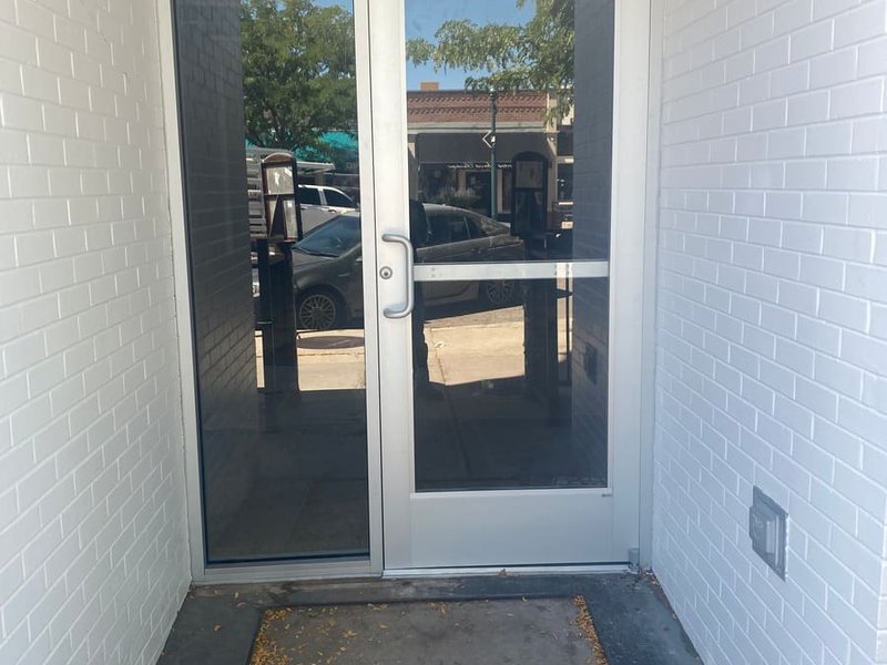 Aluminum commercial entry door with panic hardware and glass sidelite in a storefront vestibule by Kent Glass