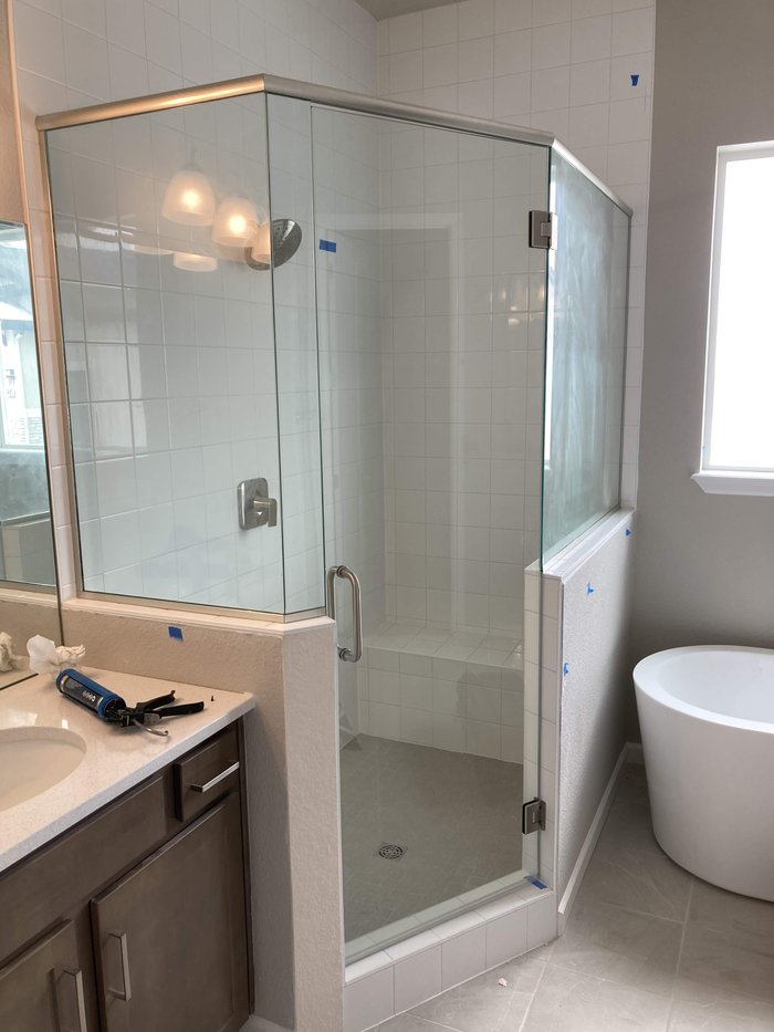 Frameless neo-angle shower enclosure with header and brushed nickel hardware