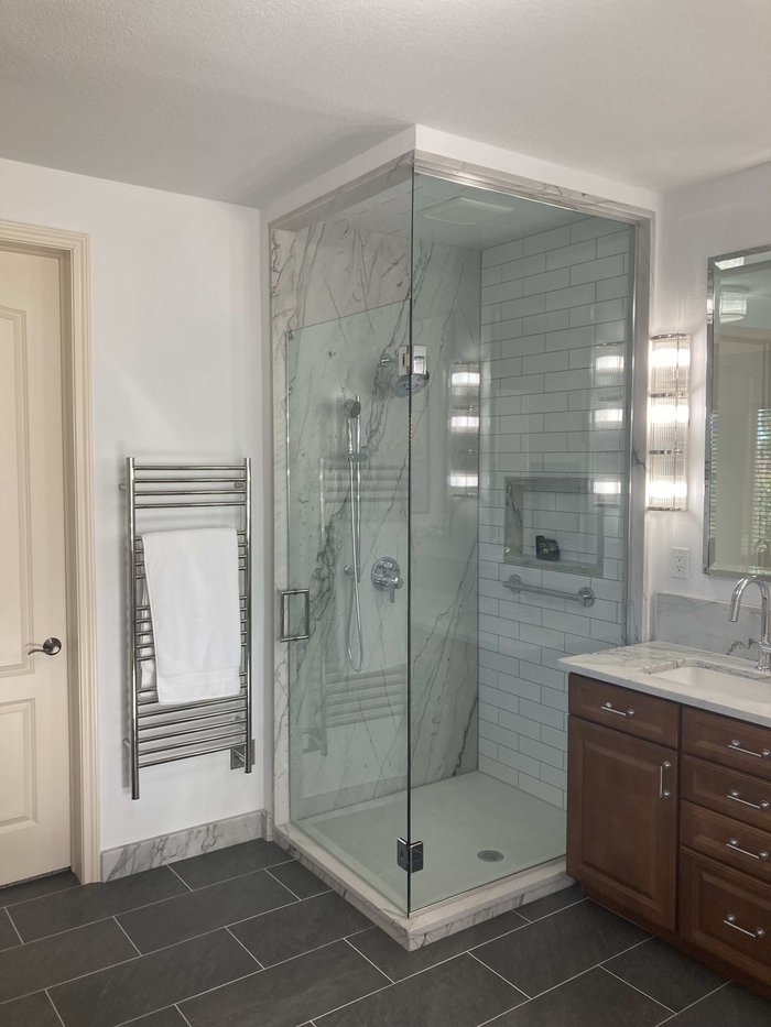 Frameless specialty-design shower enclosure with chrome hardware and marble surround