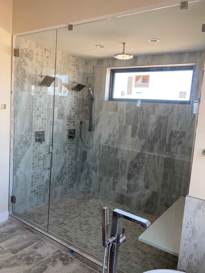 Frameless steam shower with chrome clips and gray marble tile