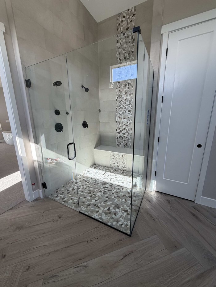 Frameless swing-door shower with matte black hardware and mosaic tile accents